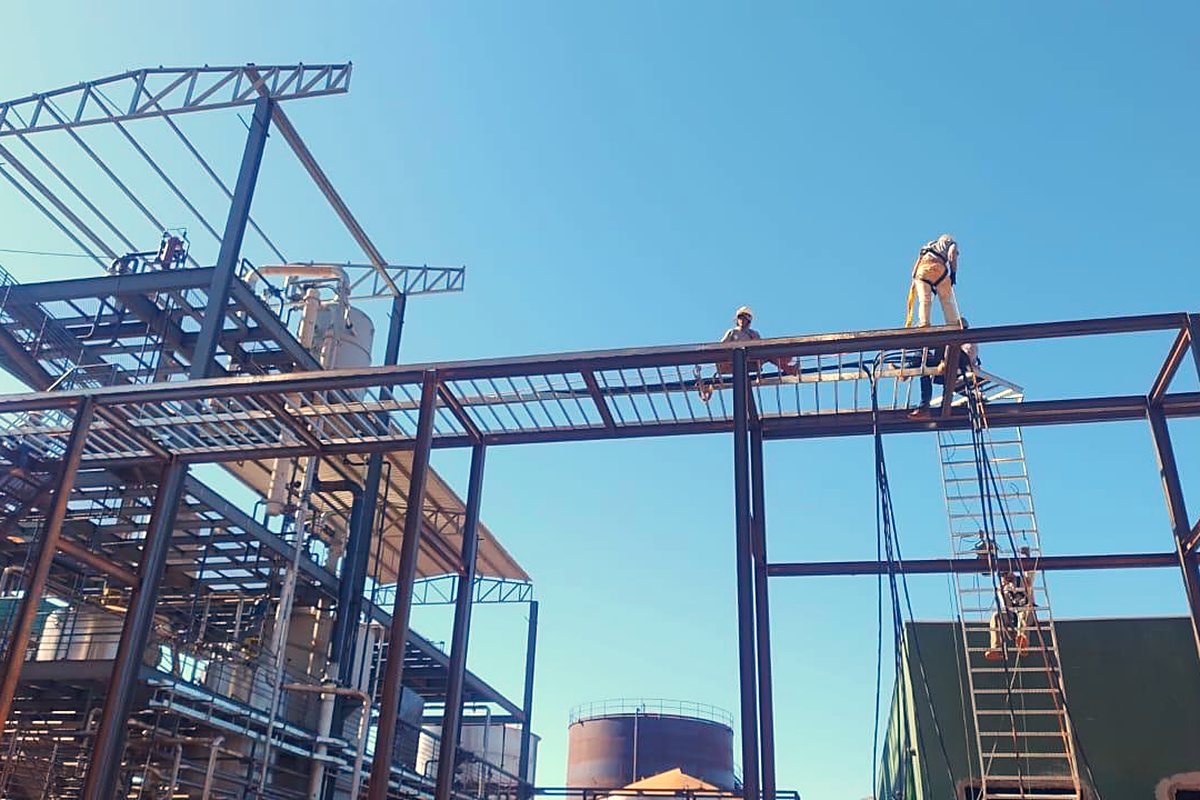 Montagem de estrutura metálica do pipe rack com trabalhador em altura