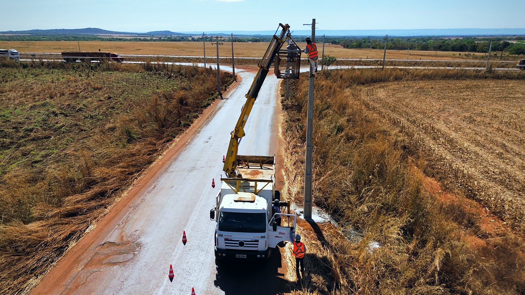 Rede de alta tensão implantada ao longo de via em área aberta, com postes alinhados até o horizonte