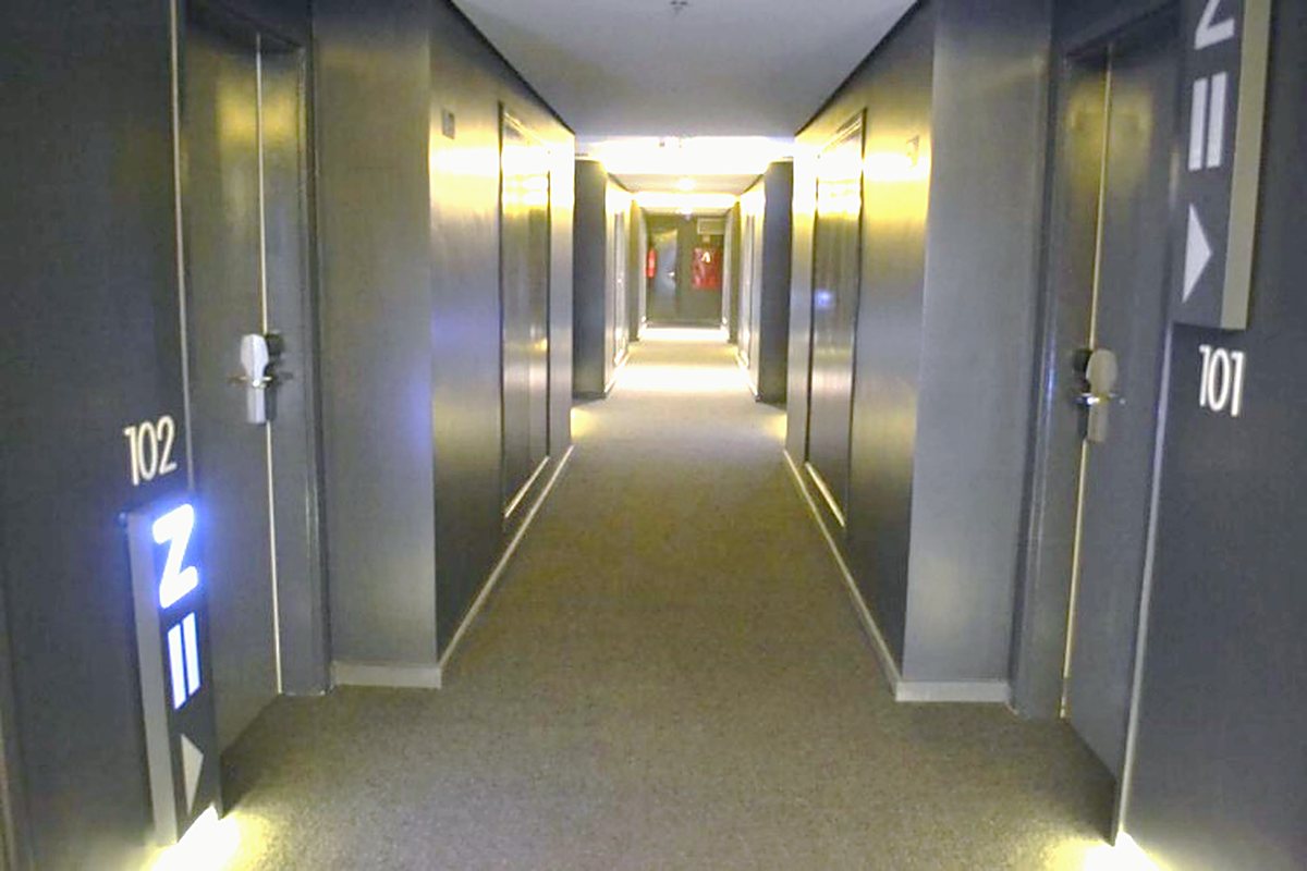 Circulação de andar do hotel com iluminação embutida e sinalização de unidades