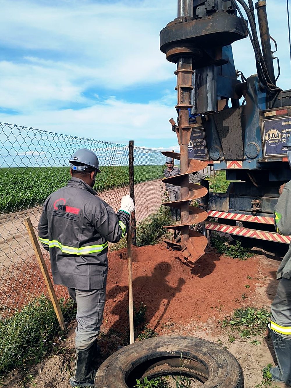 Operador acompanha perfuratriz abrindo cava para fundação de poste em solo de lavoura