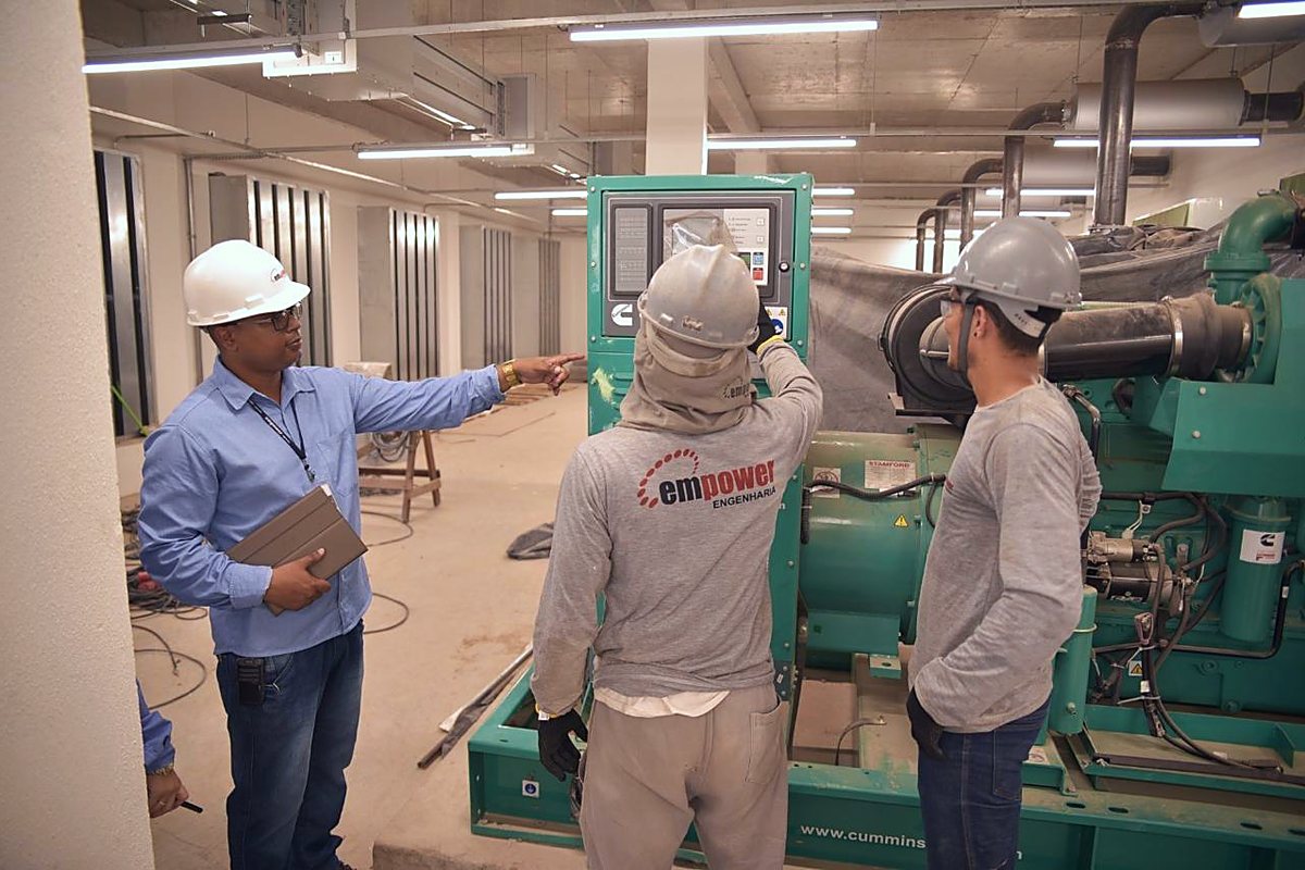 Equipe técnica em serviço junto a equipamento na casa de máquinas