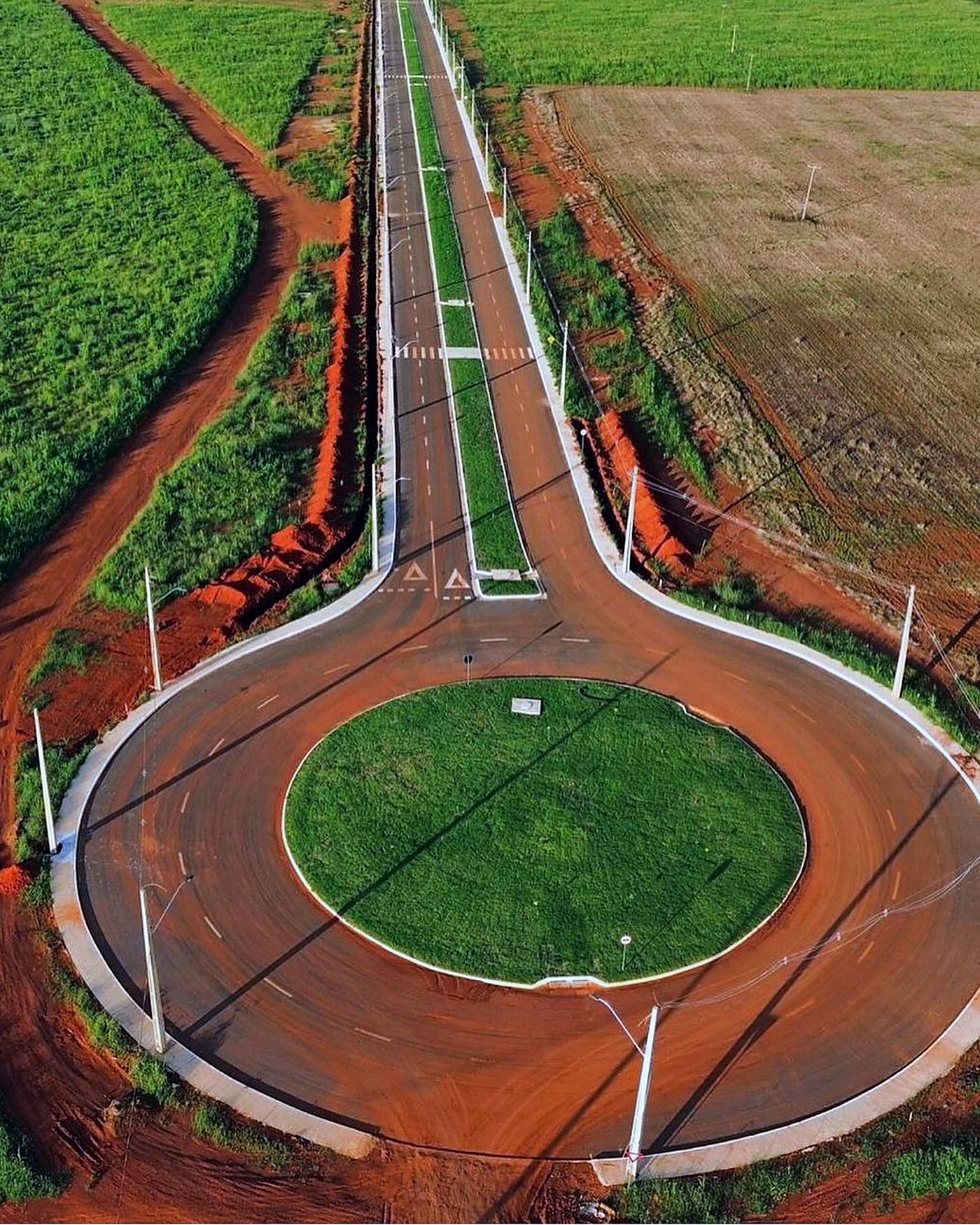 Vista aérea de rotatória pavimentada e vias do loteamento industrial recém-implantado